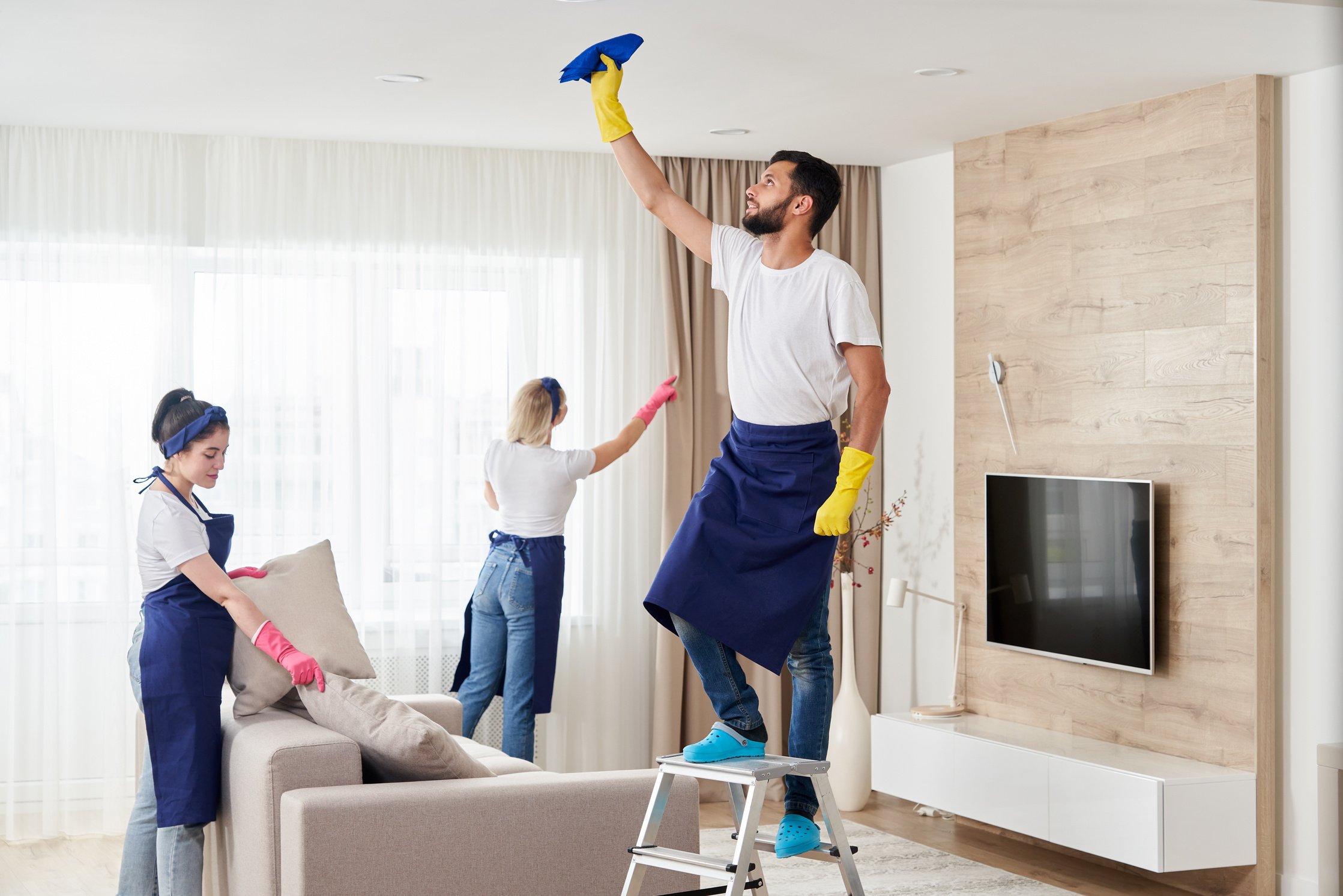 Professional cleaning service team cleans living room in modern apartment